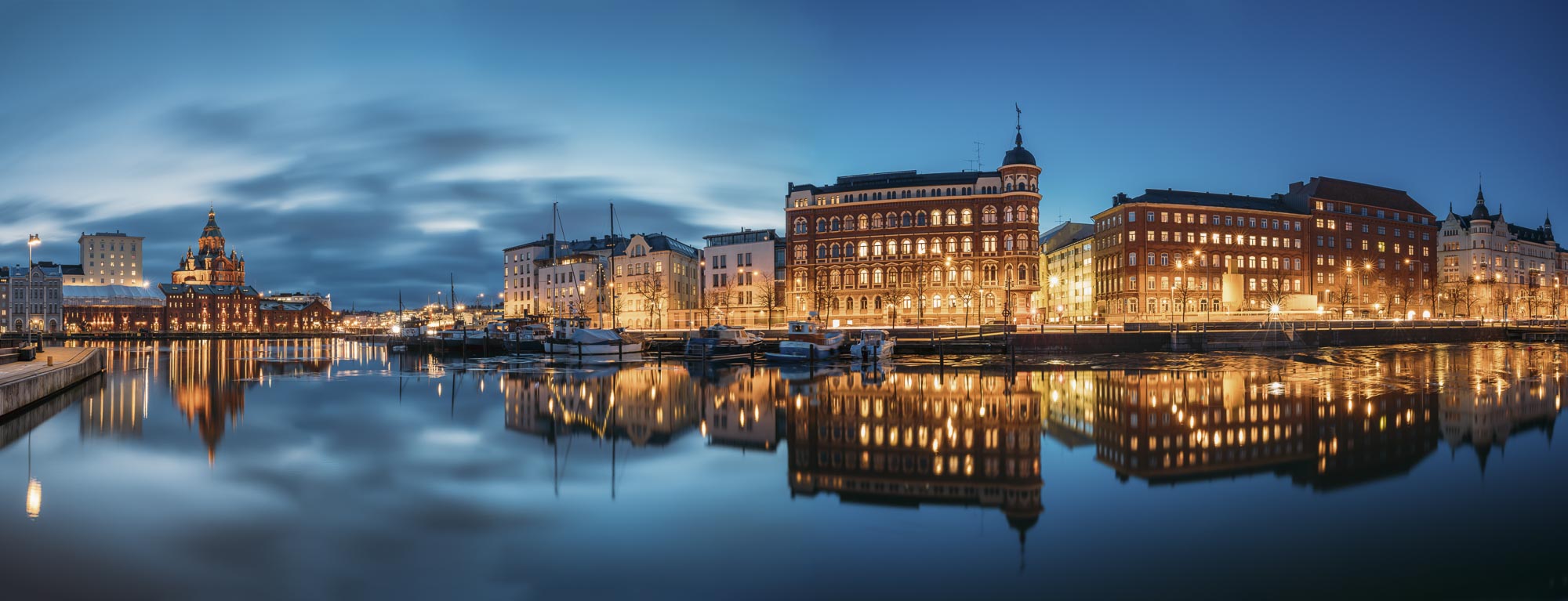 Helsinkis beleuchtete Hafenfassaden spiegeln sich im Wasser