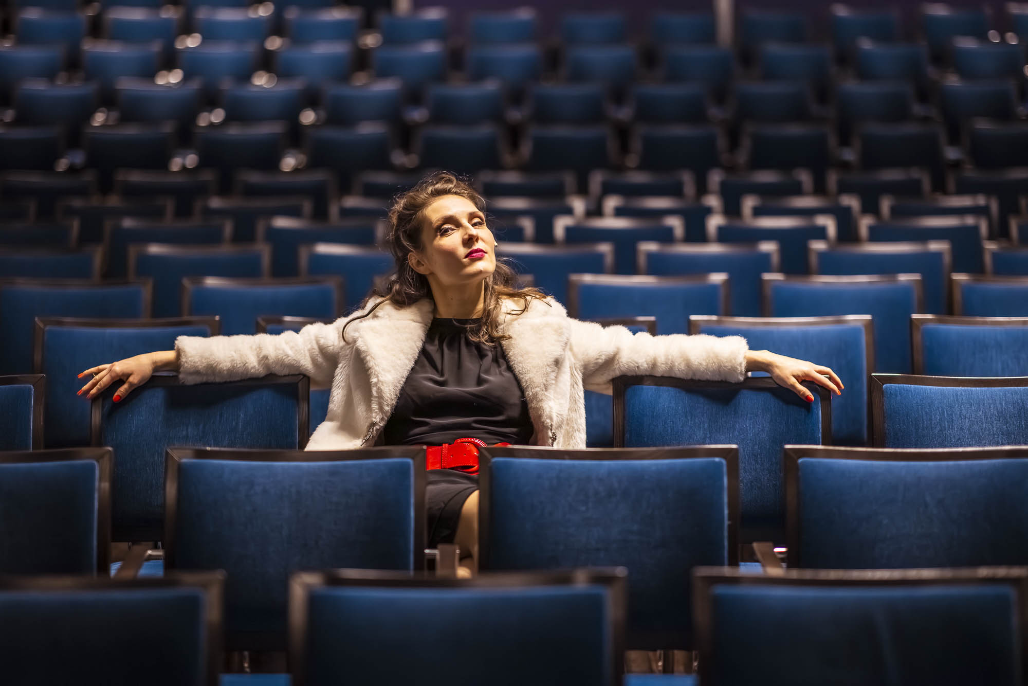 Nicole Tschaikin sitzt allein zwischen den blauen Reihen eines Theaters