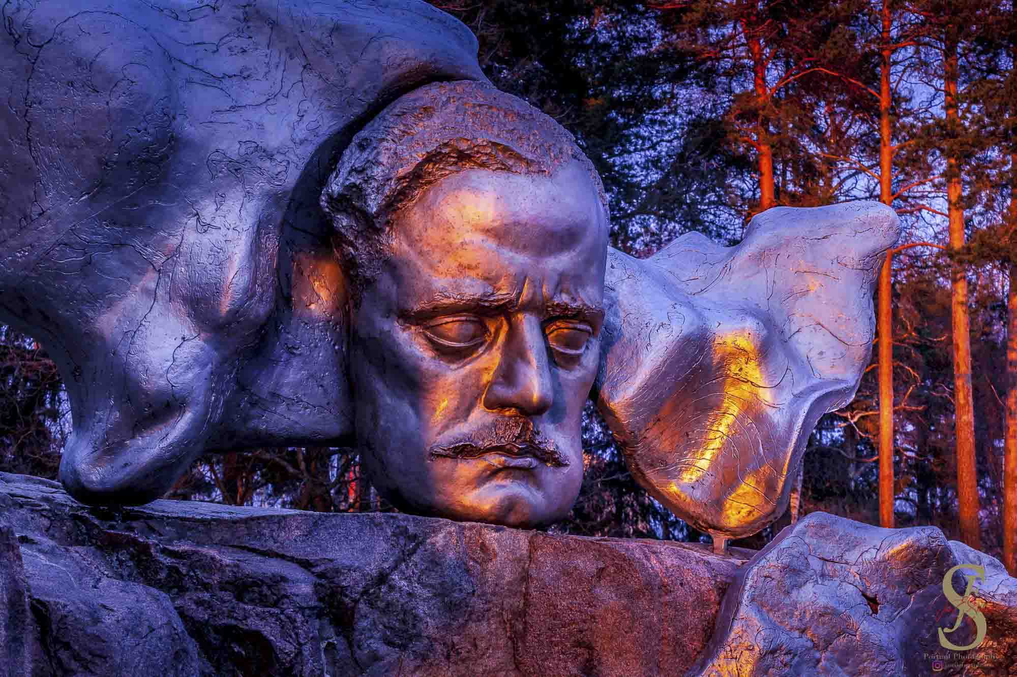 Das Porträt von Jean Sibelius am Denkmal in Helsinki im blauen und goldenen Abendlicht
